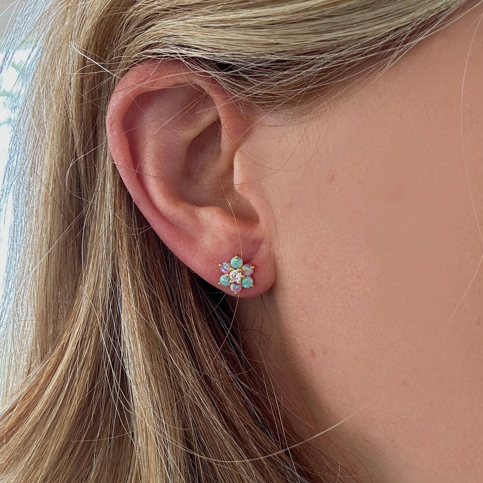 Close-up of an ear wearing a floral earring with gemstones.