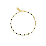 Gold bracelet with black beads on a white background