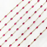 Gold chain with pink red wine enamel on a white background