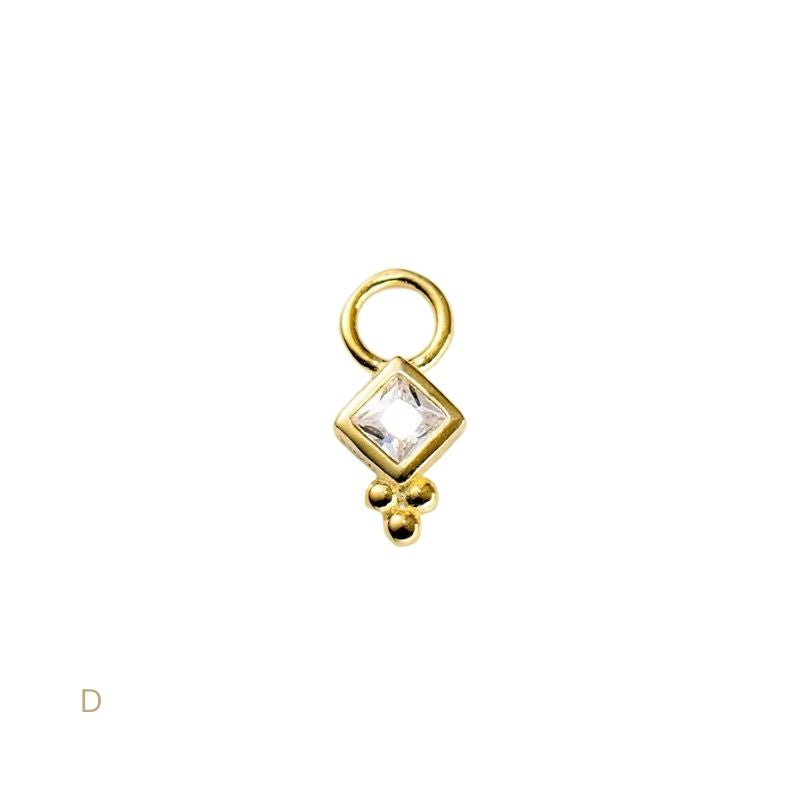 Gold charm with a square cut gemstone on a white background