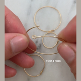 Gold hoop earrings being held by hands on a marble surface with 'Twist & Hook' text.