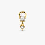 A gold ring earring featuring a round clear gemstone and a dangling heart-shaped clear gemstone, set against a plain light gray background.