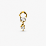 A gold ring earring featuring a round clear gemstone and a dangling heart-shaped clear gemstone, set against a plain light gray background.