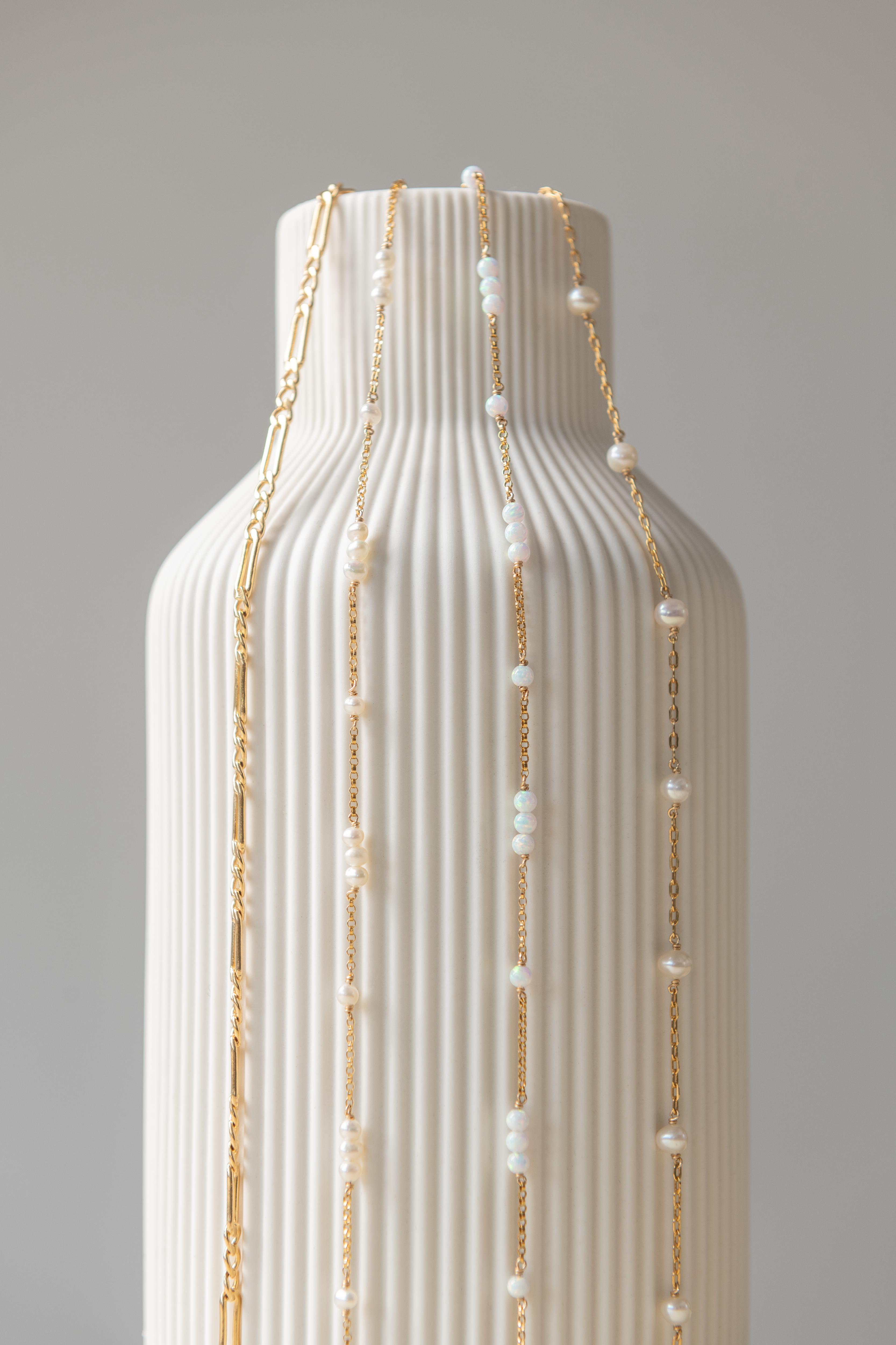 A close-up image of a bracelet with interlocked gold chains against a light background.