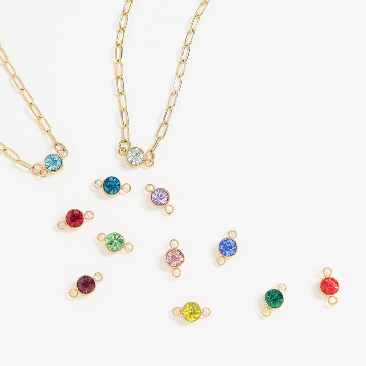 Gold necklaces with colorful gemstone pendants on a white background