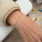 Close-up of a wrist wearing multiple gold bracelets on a neutral background