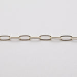 A silver paperclip chain laid out on a white surface.