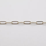 A silver paperclip chain laid out on a white surface.