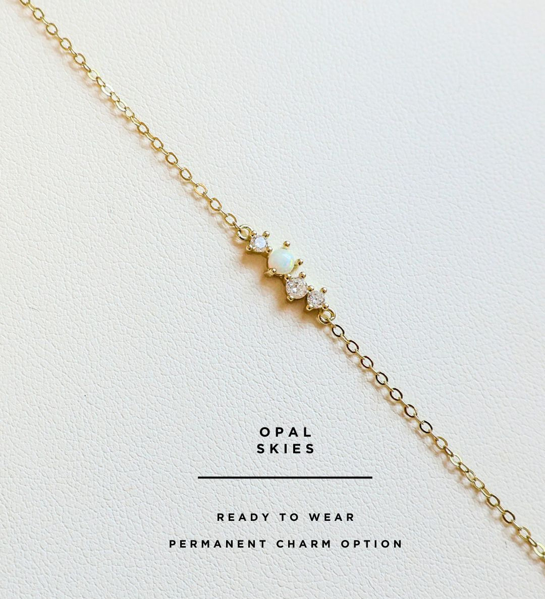 Gold permanent bracelet with opal stones on a white background, branded 'Opal Skies'.