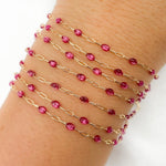 Gold chain bracelet with pink beads on a wrist against a white background