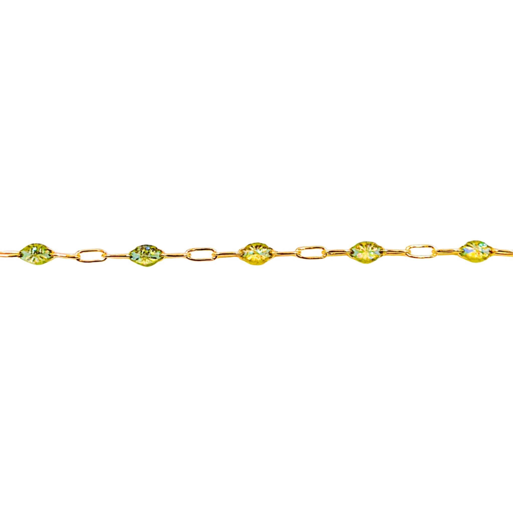 Gold bracelet with green gemstones on a white background