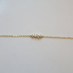 Gold bracelet with one opal and three small diamonds on a white leather surface