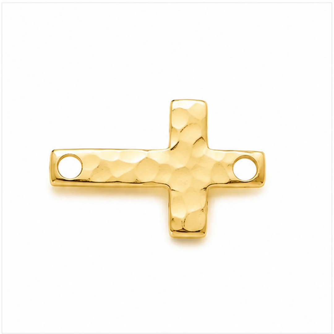 A gold cross-shaped jewelry charm with a hammered texture and two circular holes, shown on a plain white background.